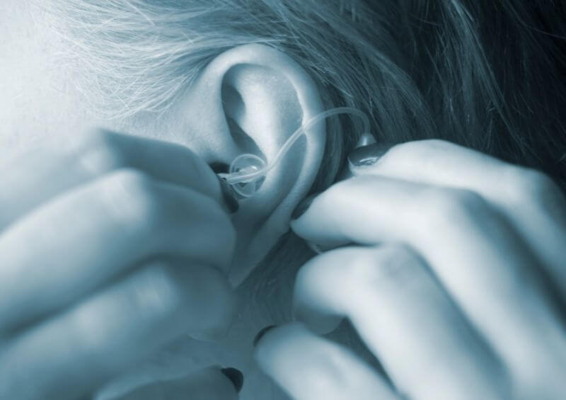 Woman putting hearing aid in ear