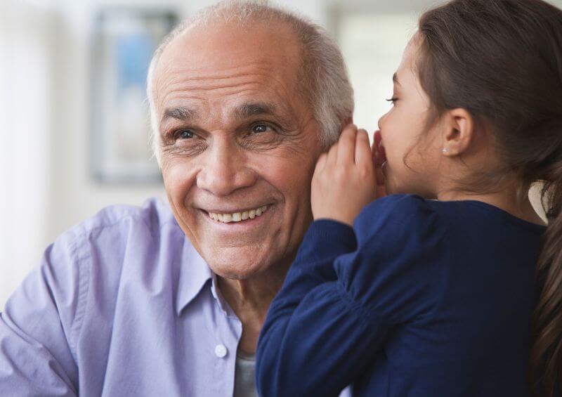 little girl whispering in grand dads ear